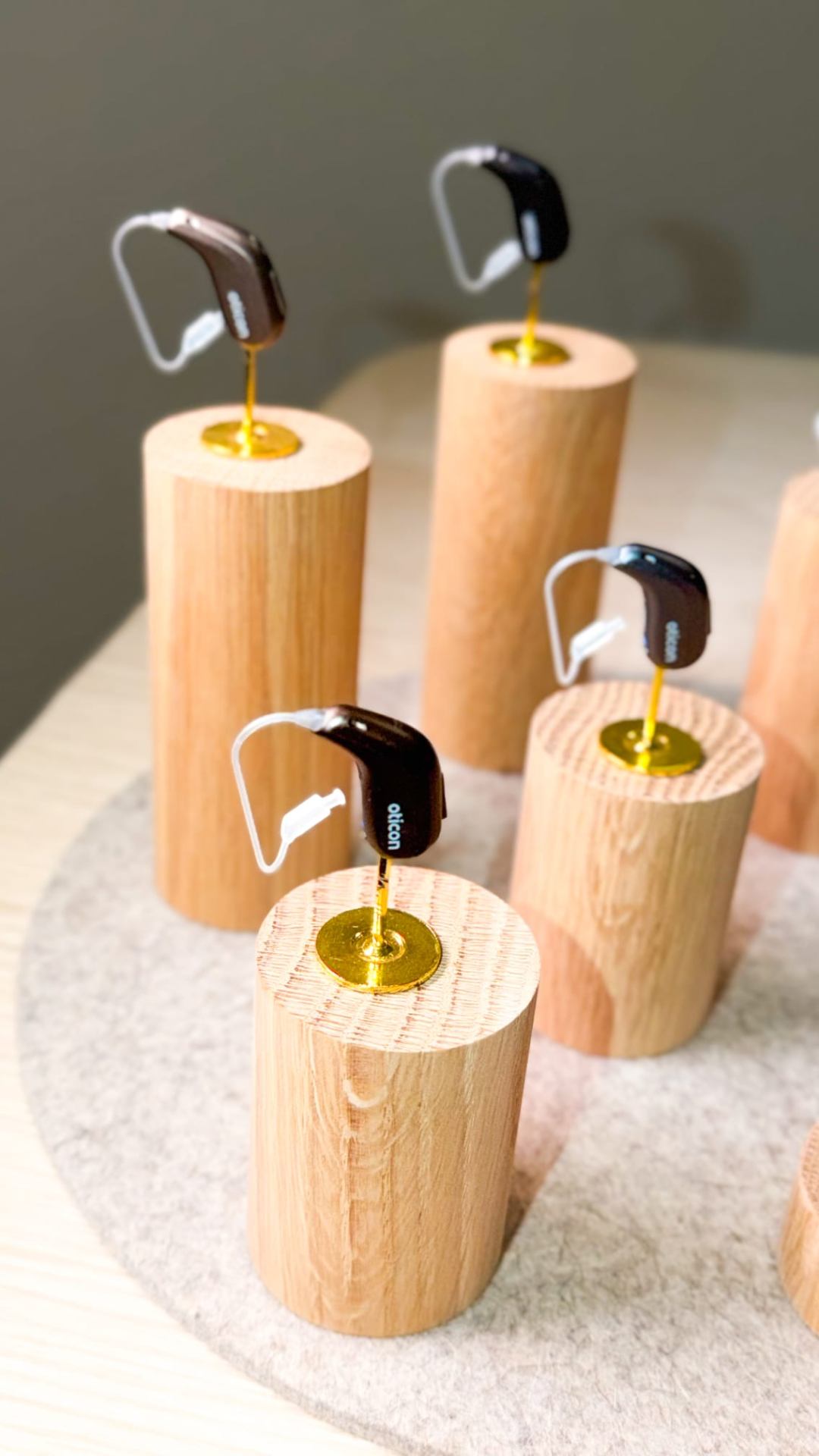 Modelos de audífonos Oticon expuestos sobre soportes de madera