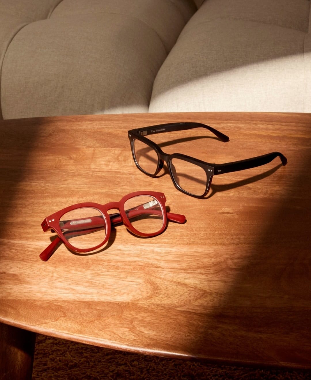 Gafas auditivas en colores negro y rojo sobre una mesa de madera